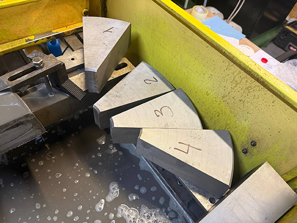 Proces wycinania elektroerozyjnego segmentów tulei do prasy hydraulicznej oraz gotowe, ponumerowane części stalowe.